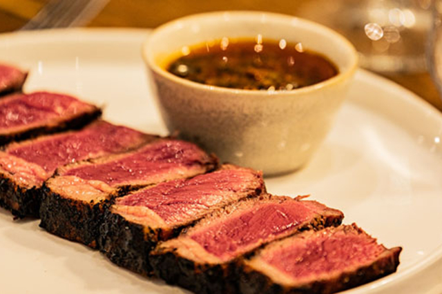 ASA Restaurant Montpellier : tranches de viande grillée, servies rosées avec une sauce dans une assiette blanche.