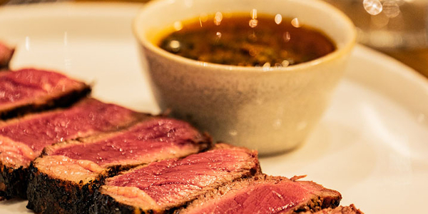 ASA Restaurant Montpellier : tranches de viande grillée, servies rosées avec une sauce dans une assiette blanche.
